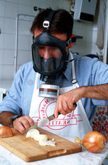Mann mit Gasmaske beim Zwiebelschneiden