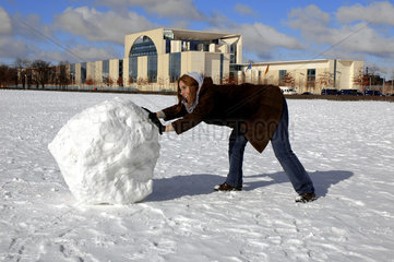 Frau rollt grosse Schneekugel