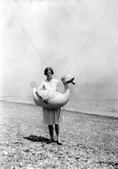 Frau steht am Strand mit grosser Plastikente Gummiente