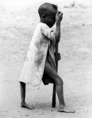afrikanischer Junge laeuft mit Krueckstock