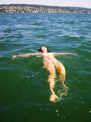 nackte Frau laesst sich im Wasser treiben