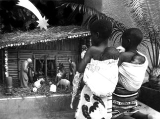 zwei Afrikanerinnen mit Kindern betrachten Krippenspiel