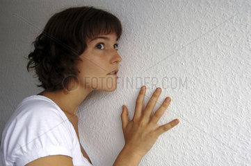 Frau lauscht an Wand