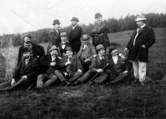 Maennergruppe sitzt auf Wiese  1910