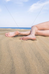 Beine einer Frau am Sandstrand