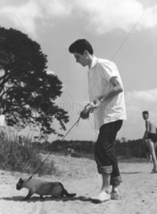Mann am Strand mit Katze an Hundeleine