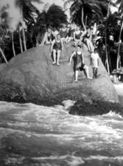 Jugendliche posieren auf einem Stein am Wasser