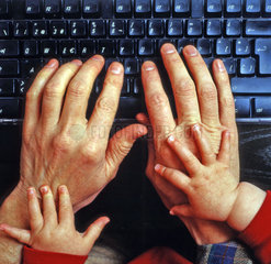 Babyhaende auf alten Haenden auf einer Tastatur