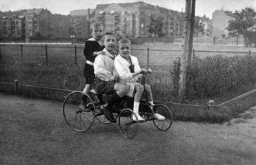 drei Kinder auf historischem Fahrrad