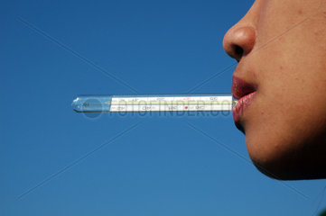 Frau mit Fiebertermometer im Mund