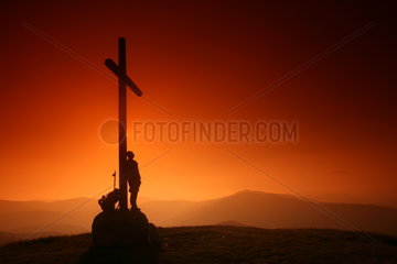 Mann lehnt an Kreuz am Jakobsweg - Camino de Santiago