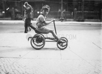 Kleiner Junge auf einem Vierrad