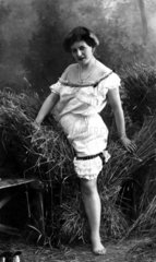 1910 Frau im Nachthemd zwischen Stroh