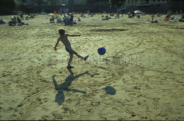 Junge spielt Ball am Strand