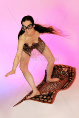 Frau reitet in sehr kurzem Rock stehend auf fliegendem Teppich