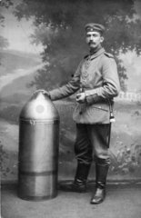 Soldat posiert neben grosser Munition - Artillerie