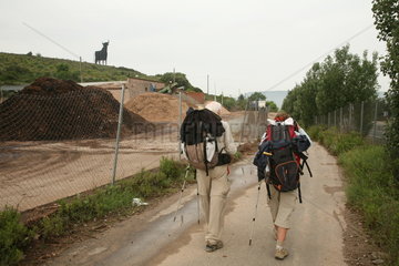 zwei Pilger auf dem Jakobsweg kommen an Zaun vorbei - Camino de Santiago