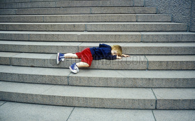 Junge liegt auf Treppenstufen