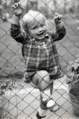 kleines Maedchen klettert ueber den Zaun
