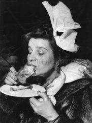 Frau mit Serviette im Haar isst fettiges Stueck Fleisch