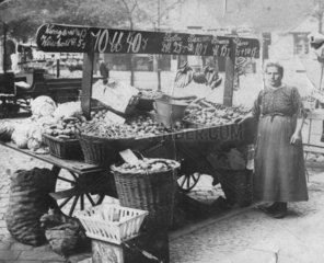 Frau verkauft Gemuese an Marktstand