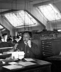 Mann mit traditionellem Schnauzer telefoniert in Grossraumbuero