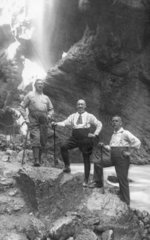 Drei Maenner vor Wasserfall