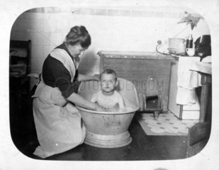 Frau badet Jungen in kleiner eiserner Badewanne