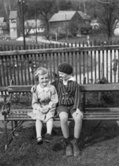 zwei Maedchen sitzen auf einer Parkbank