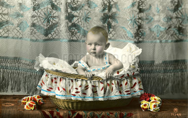 Baby sitzt in Korb  1905