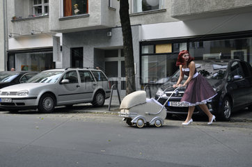 Frau mit Kinderwagen ueberquert die Strasse