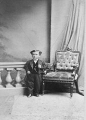 Liliputaner posiert neben einem Stuhl