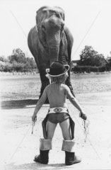 Junge als Cowboy vor Elefant