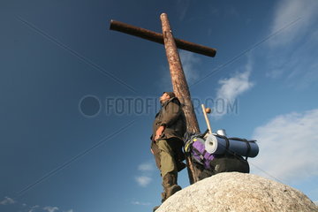 Pilger lehnt an Kreuz am Jakobsweg - Camino de Santiago