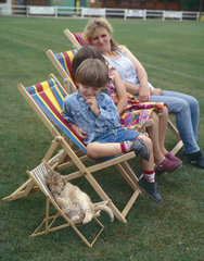 Mutter mit Kindern und kleinem Loewen im Liegestuhl