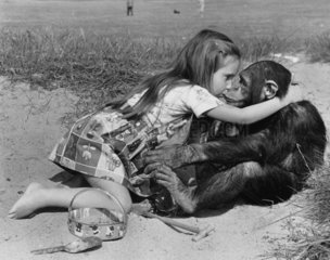 Maedchen kuesst Schimpanse am Strand