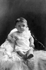 Baby sitzt auf Eisbaerfell  1910
