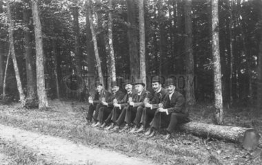 Gruppe Maenner sitzt auf einem Baumstamm