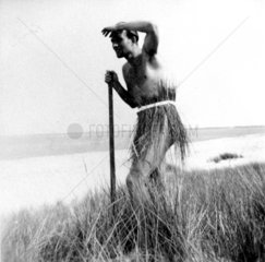 Mann mit Bastroeckchen steht im Schilf 1920
