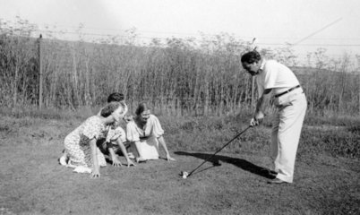 Frauen beobachten Mann beim Golfen