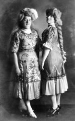 zwei Frauen in pompoesen Kleidern mit grossen Peruecken
