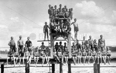 Jugendliche Schwimmer posieren in Badehosen auf Sprungturm
