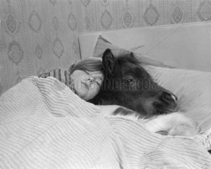 Kind schlaeft mit Esel im Bett