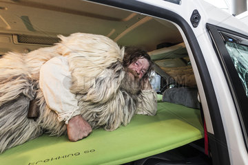 Ein Karnevalist als Yeti gekleidet liegt Probe auf dem Auto-Bett von *YATOO concept*