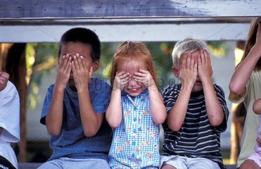 drei Kinder halten sich die Augen zu