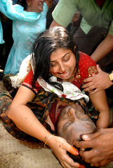 A woman cries holding her relative's dead body
