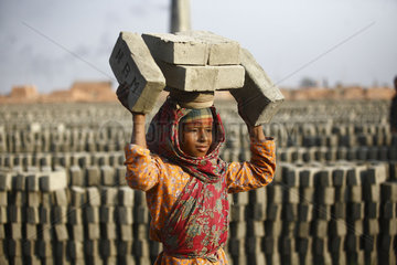 Girl child worker carrying bricks