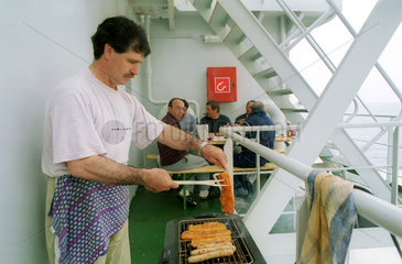 Matrose grillt Fleisch fuer die Mannschaft (Ostsee)