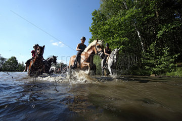 Oberoderwitz  Maedchen reiten mit ihren Pferden durch einen See