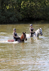 Oberoderwitz  Maedchen reiten mit ihren Pferden durch einen See